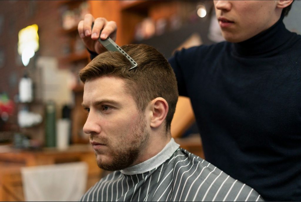 Barber styling hair with clippers at a Houston barbershop, offering top-notch grooming services.