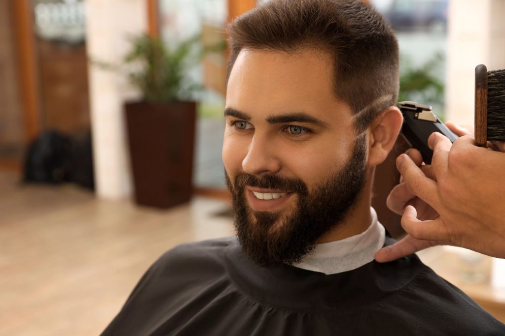 Barber giving a fade haircut at a Houston barbershop, showcasing expert grooming skills.