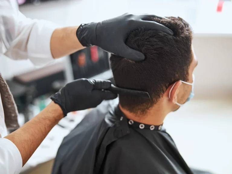 Professional barber cutting hair at a modern barber shop with gloved hands and comb.
