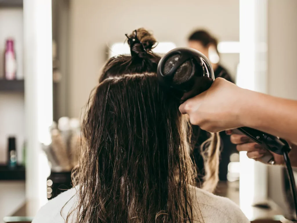 A skilled barber from Barbers in Houston drying a client's wet hair with a professional hairdryer in a modern salon