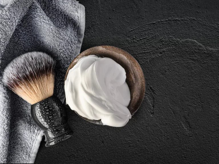 Close-up of a luxurious shave setup with a shaving brush and rich foam in a bowl, paired with a soft towel, ideal for a premium Haircut and Shave Houston experience.