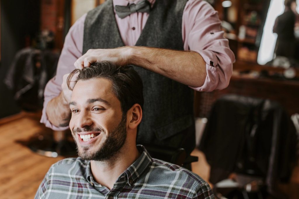 Happy client receiving a haircut at a cozy barbershop with a skilled barber styling hair.