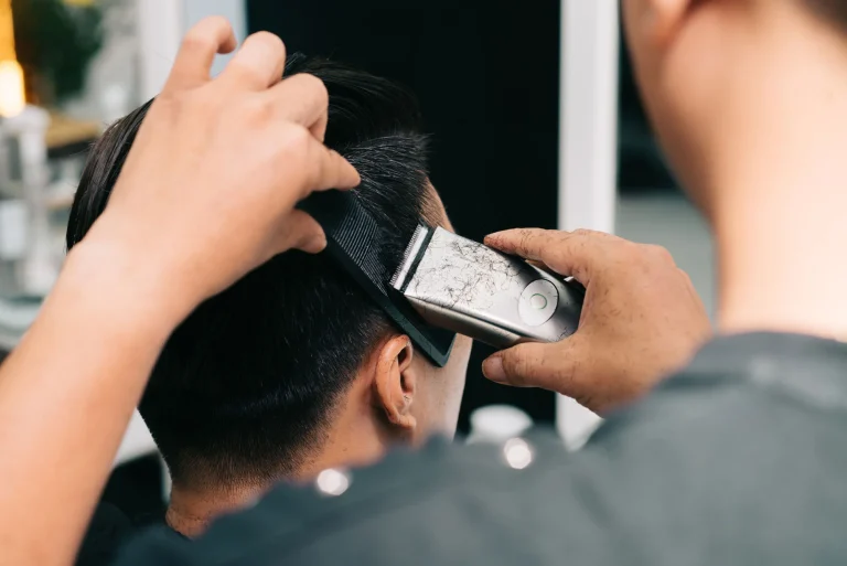 Close-up of a barber giving a haircut with clippers in a modern salon setting.