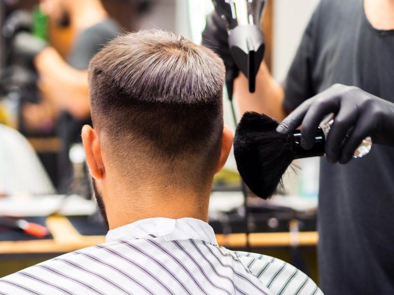 Close-up of a barber brushing hair after a haircut in a busy salon with modern equipment.