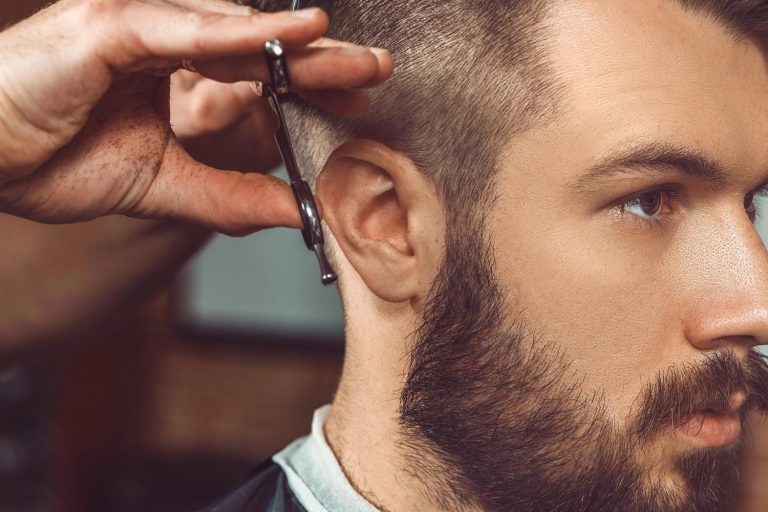 Barber trimming hair with scissors for a sharp men's haircut in a professional barbershop setting.
