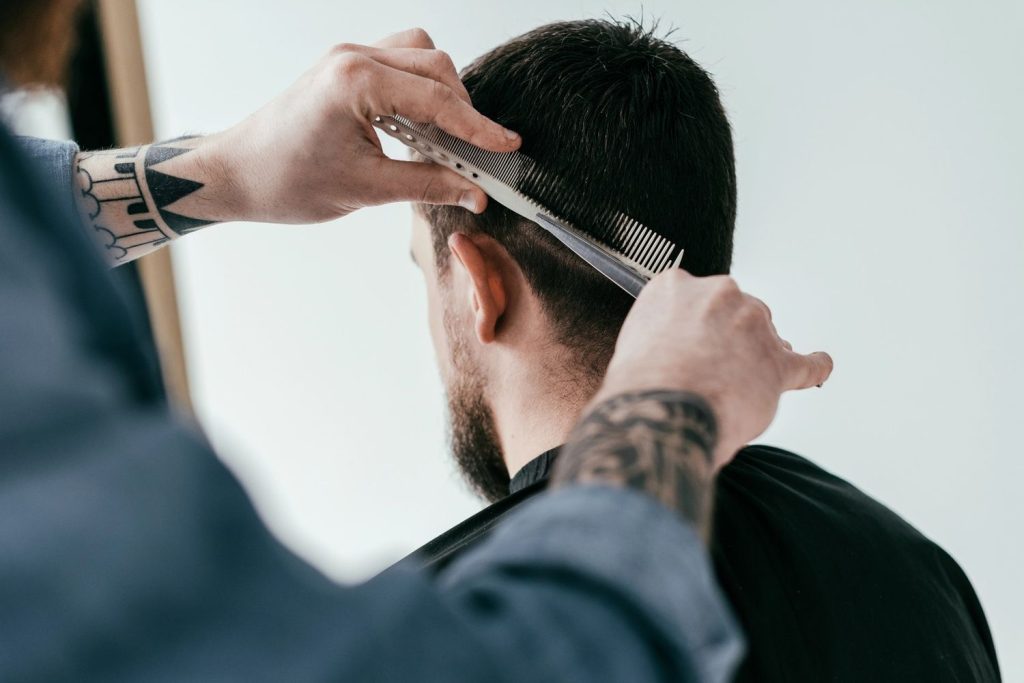 Barber styling hair with comb at a walk in barber shop, offering quick and expert haircuts.