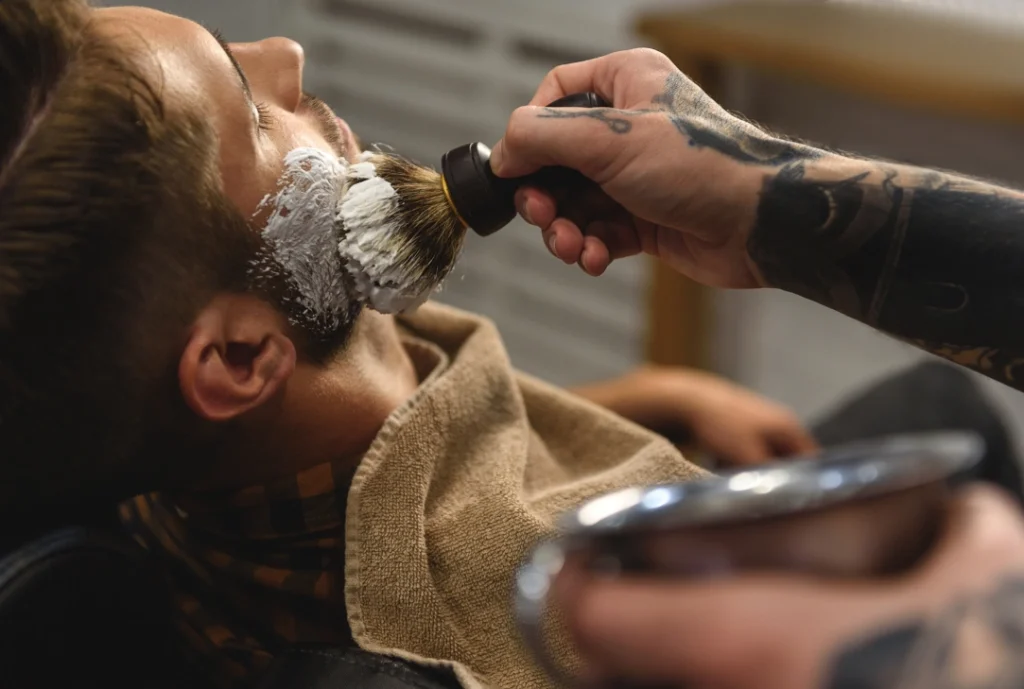 Close-up of a barber using a badger brush to apply shaving cream for a classic Mens Shave Houston.