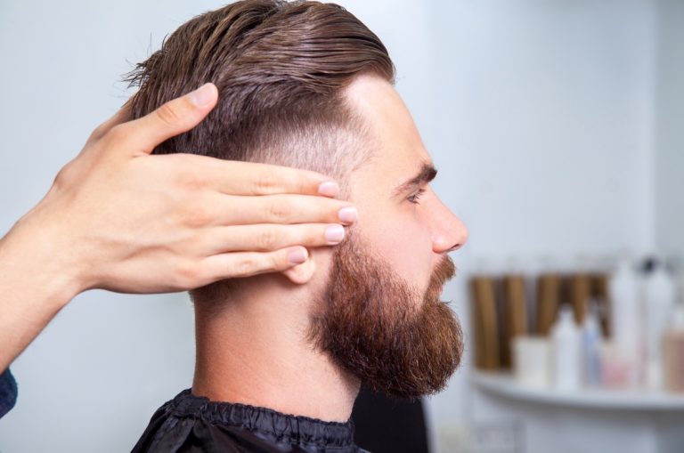 Side profile of a bearded man getting a fresh short-fade haircut at a professional Barber Shop.